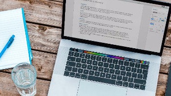Laptop, notebook and glass on a wooden desk