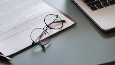 Documents and glasses beside a laptop